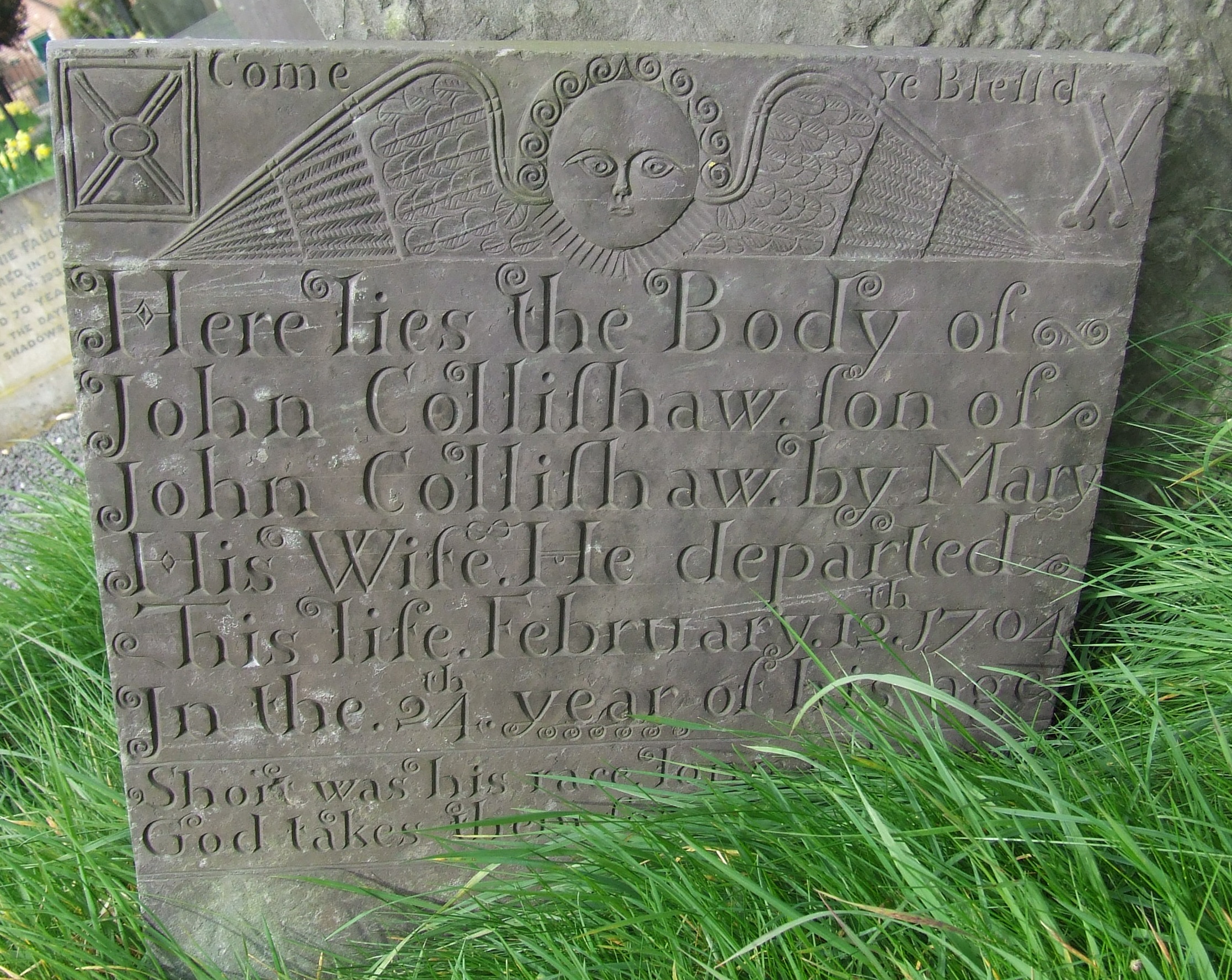 A headstone with a cherub motif and other mortality symbols